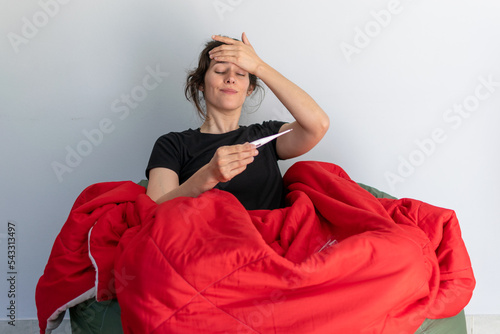 Con fiebre y midiendo la temperatura corporal con termómetro 