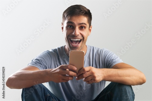 Young man holding mobile phone, winning concept