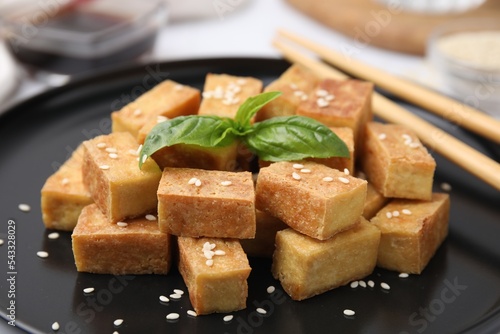 Plate with delicious fried tofu, basil and sesame seeds, closeup
