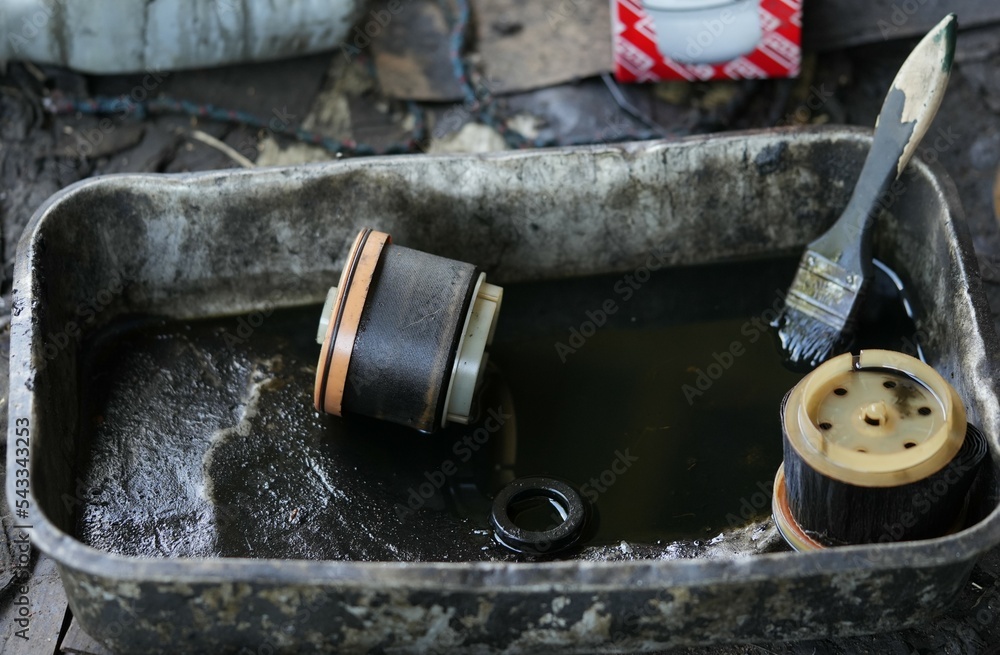 oil filter Placed in a tray filled with black engine oil.