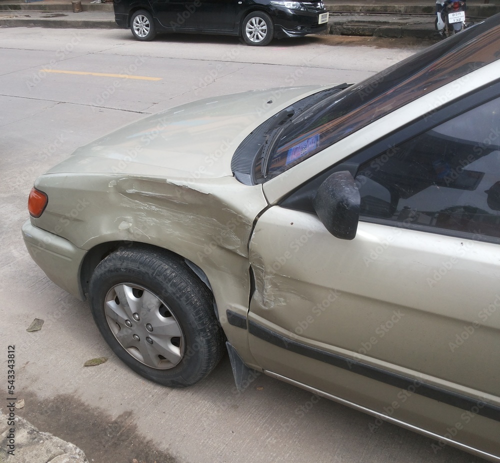 Gold color car's dent beside left wheel from an accident.