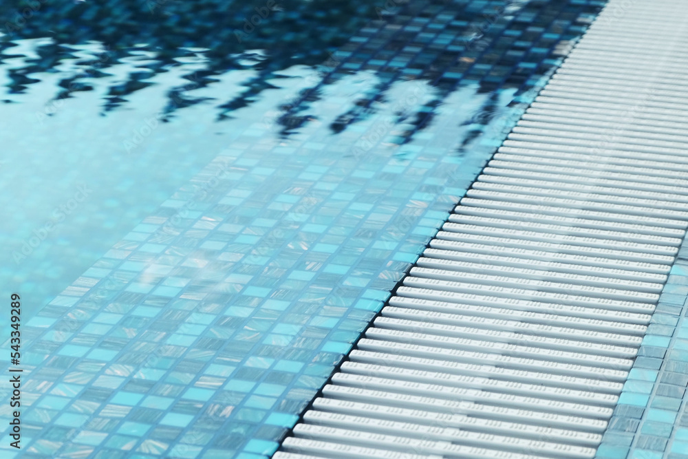 Obraz premium Close-up of the pool edge in blue mosaic tiles. Clear blue water in the pool. Relax in the backyard of a country house