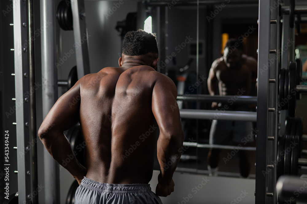Handsome afro american man posing showing back muscles in gym. Handsome afro american man posing showing back muscles in gym.
