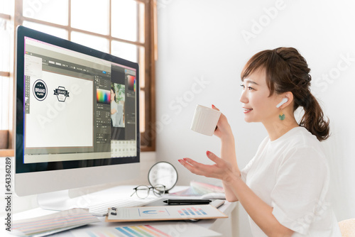 イヤホンを使ってオンラインミーティング・WEB会議するデザイナーのアジア人女性
 photo