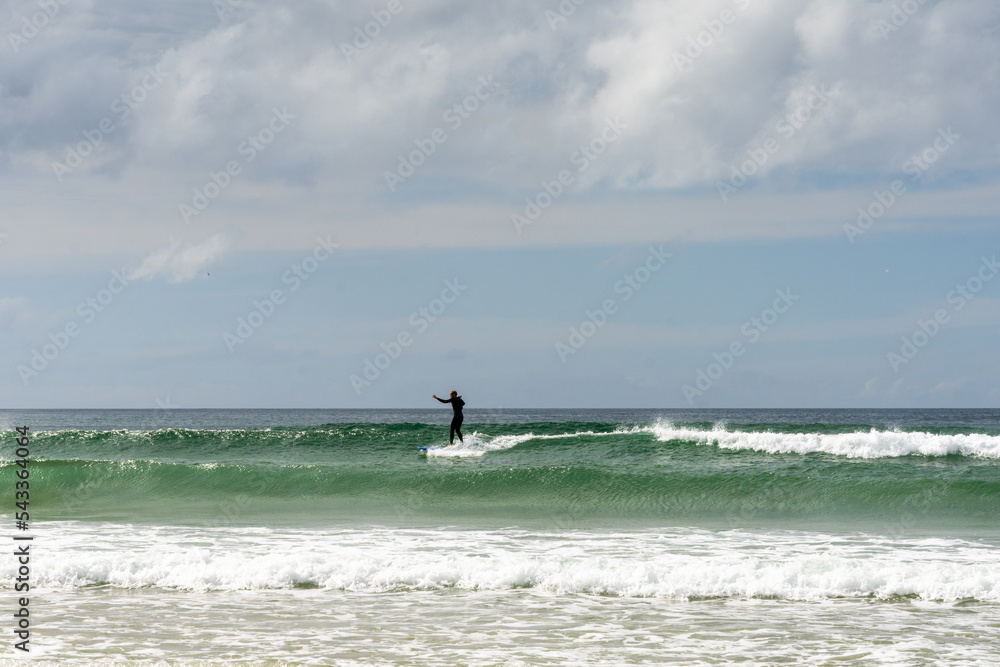 surfer catching a wave at Fistral Beach in Newquay