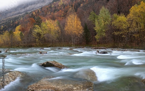 Rio Arazas flowing on rocks in a fall forest in Ordesa y Monte Perdido National Park. Huesca, Spain photo