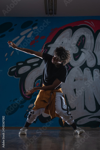African American hip hop dancer  breakdancer  performing over graffiti background in dark silhouette exposure.