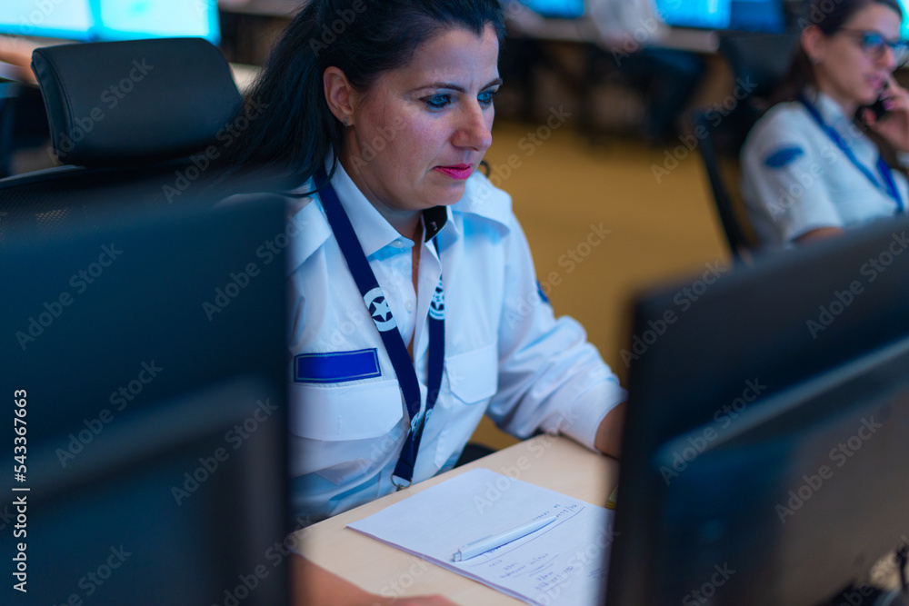 Happy security data center operator colleagues (coworkers) smiling and monitoring the CCTV footage while typing on a keyboard. Happy security data center operator colleagues (coworkers) smiling and monitoring the CCTV footage while typing on a keyboard.