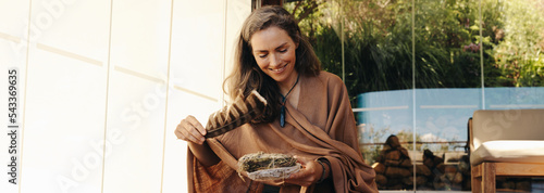 Happy senior woman preparing to burn sage with a feather at home photo