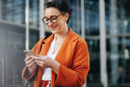 Happy business woman reading a text message on her phone while commuting to work in the city photo