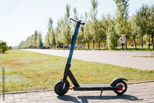Electric scooter parked in the park on a sunny summer morning