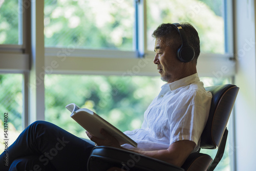 音楽を聴きながら読書をする日本人シニア男性