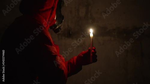 Ukraine war. Shelter. Bunker, nuclear war, a man in a gas mask and protective clothing is hiding in a bomb shelter, electricity is turned off, a man is lighting a candle, he is scared photo