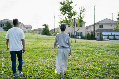 公園を散歩する日本人シニア夫婦の後ろ姿