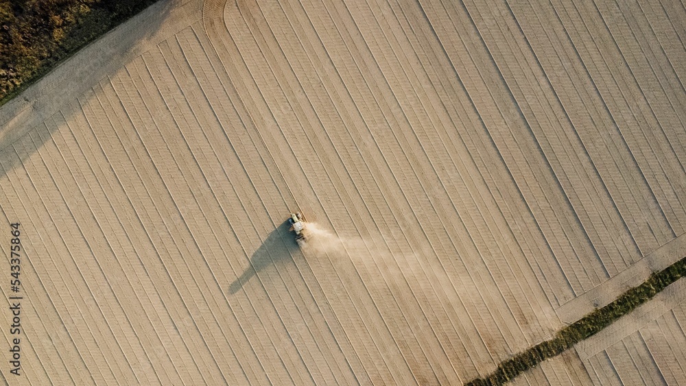 Fototapeta premium Aerial view of tractor extruding ground to compact soil levelling rural field