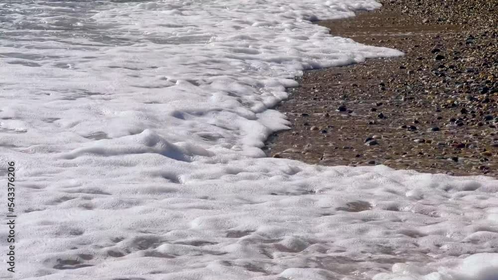 Waves crashing on empty sandy beach with pebbles. Blank natural summer background with copy space. Relaxing and calming video in 4k resolution. Sun reflection on rippled sea surface Waves crashing on empty sandy beach with pebbles. Blank natural summer background with copy space. Relaxing and calming video in 4k resolution. Sun reflection on rippled sea surface