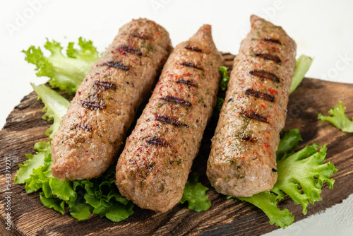 Sausages close-up grilled on a wooden crafting board, light background. Lula kebab. Without meat. Soy sausages. photo