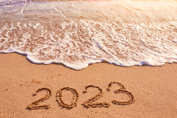 2023 year written on sandy beach sea at sunny day