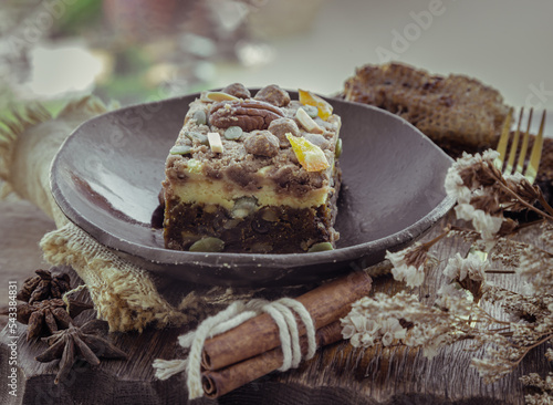 Homemade spiced pumpkin cream cheese chinnamon cake bars frosting decorated with pecan nuts and pistachio sliced into squares on ceramic plate served with brass fork. The concept of delicious dessert.