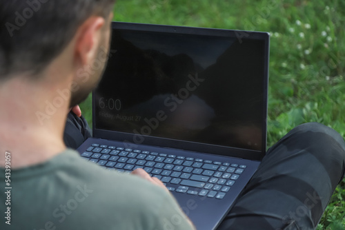 Man with laptop outdoors closeup, back view
