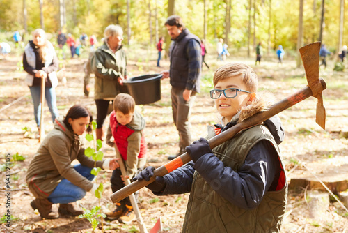 Freiwillige und Kinder beim Baum pflanzen im Wald photo