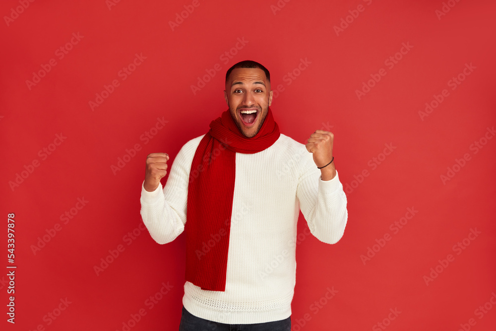Fototapeta premium Winner Man Rejoicing Studio. Extremely Happy Multiracial Guy Raised Arm Gesturing Yes I Did It, I'm Winner, Feeling Energetic and Lively. Isolated on Red Background 