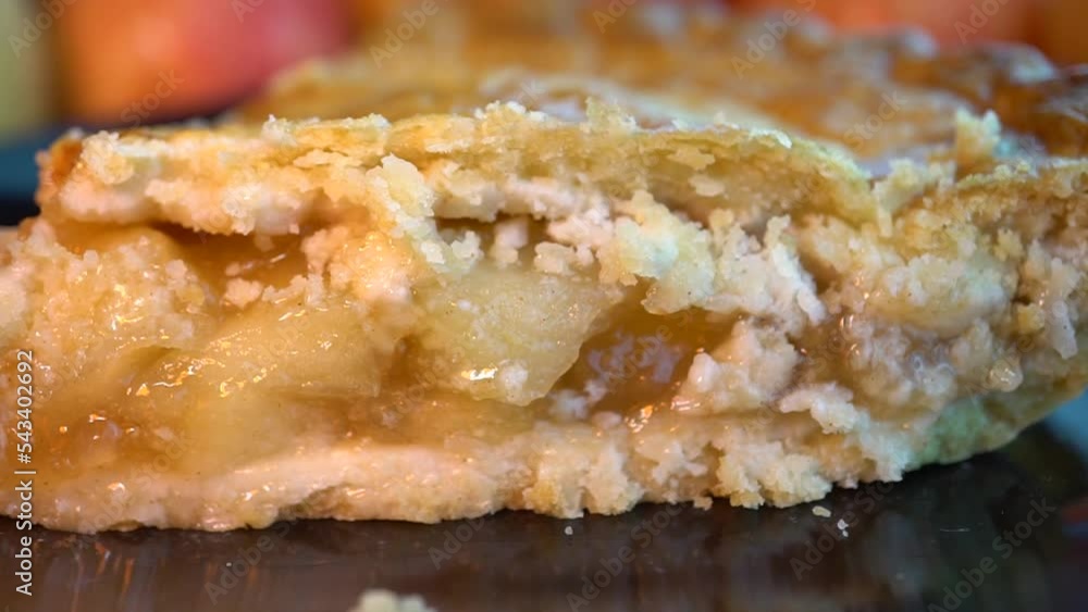 Close up of a flaky apple pie on a dark plate and red and white checker cloth Close up of a flaky apple pie on a dark plate and red and white checker cloth