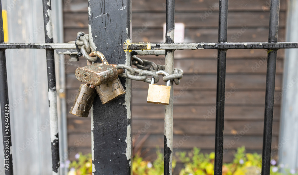 Closed on a chain padlock hanging on a metal gate Closed on a chain padlock hanging on a metal gate