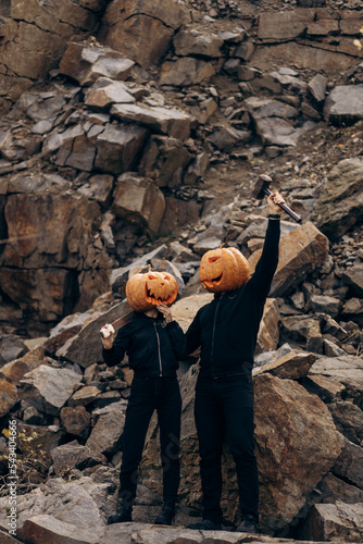 Halloween holiday lovers stand in a pumpkin on their heads