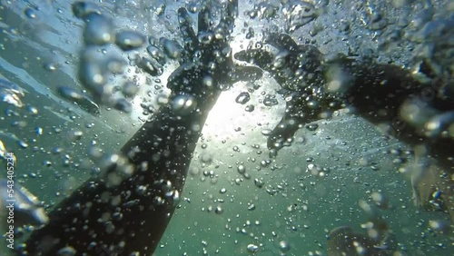 Drowning Man POV Looking at Sun and Reaching into Surface Underwater Slow Motion photo