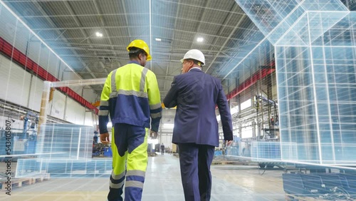 Back view of engineer and businessman walking at manufacturing plant with holographic room scan