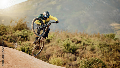 Bicycle, biker and jump in air for competition, mountain biking and extreme sport with helmet, outdoor and in nature. Athlete, bike and cycling for fun, freedom and health for adventure and wellness photo