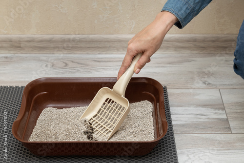 Photo man cleans cat litter with a shovel