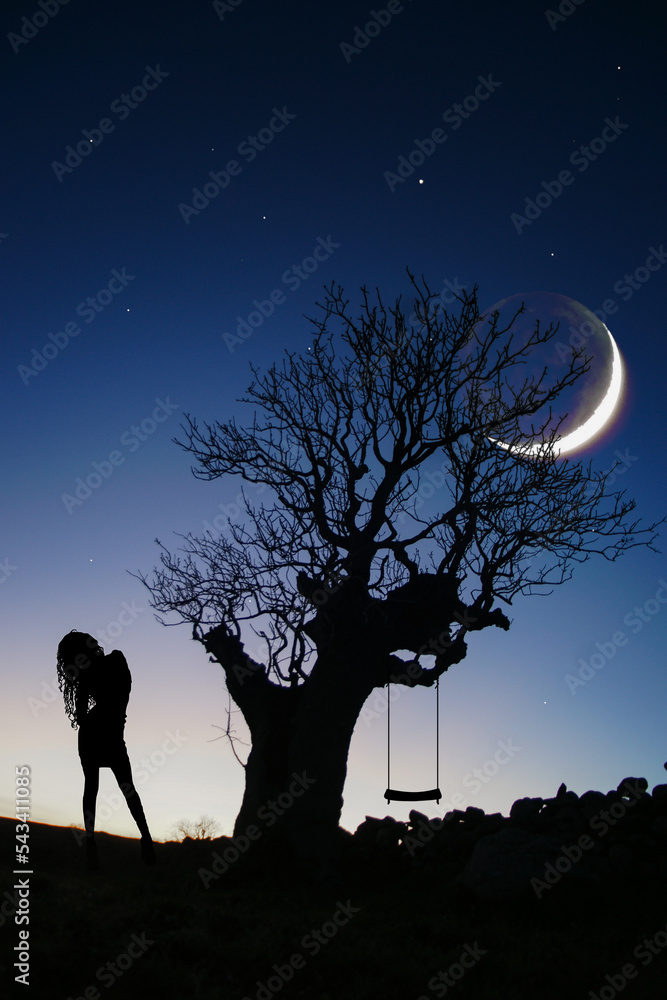 a large pistachio tree at night and a silhouette of a woman