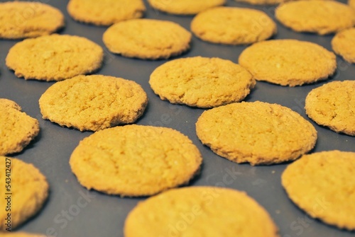 Yellow gingerbread cookies arranged symmetrically on a black baking sheet