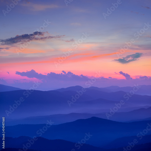 mountain chain silhouette in dense mist and clouds at the sunset