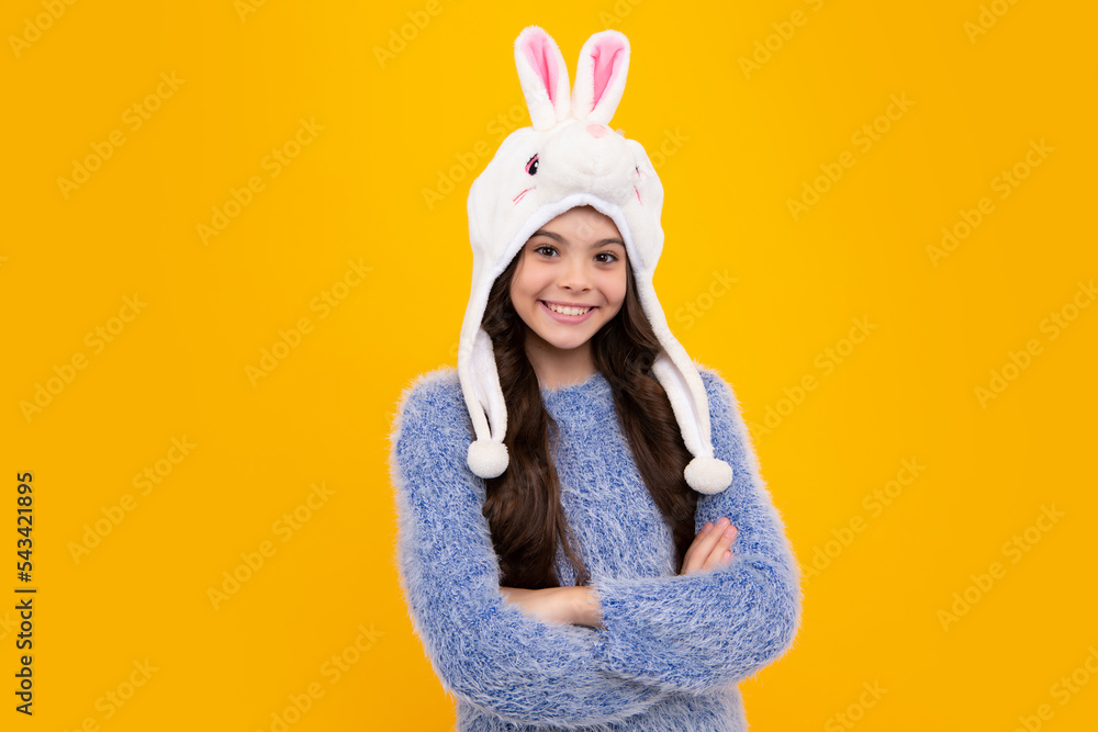 Bunny warm hat. Beautiful winter kids portrait. Teenager girl posing with winter sweater and knit hat on yellow background. Happy teenager, positive and smiling emotions of teen girl. Bunny warm hat. Beautiful winter kids portrait. Teenager girl posing with winter sweater and knit hat on yellow background. Happy teenager, positive and smiling emotions of teen girl.