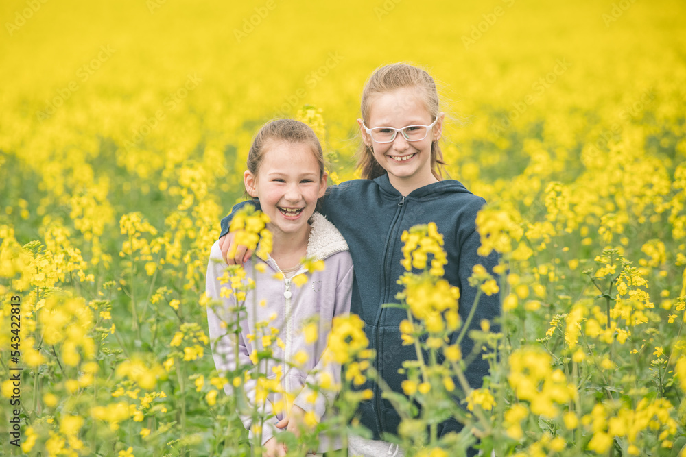 Two sisters standing in their family canola field Two sisters standing in their family canola field