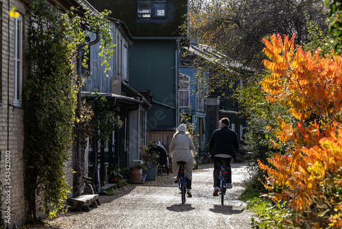 Copenhagen, Denmark, A young couple ride bikes through Christiania, photo