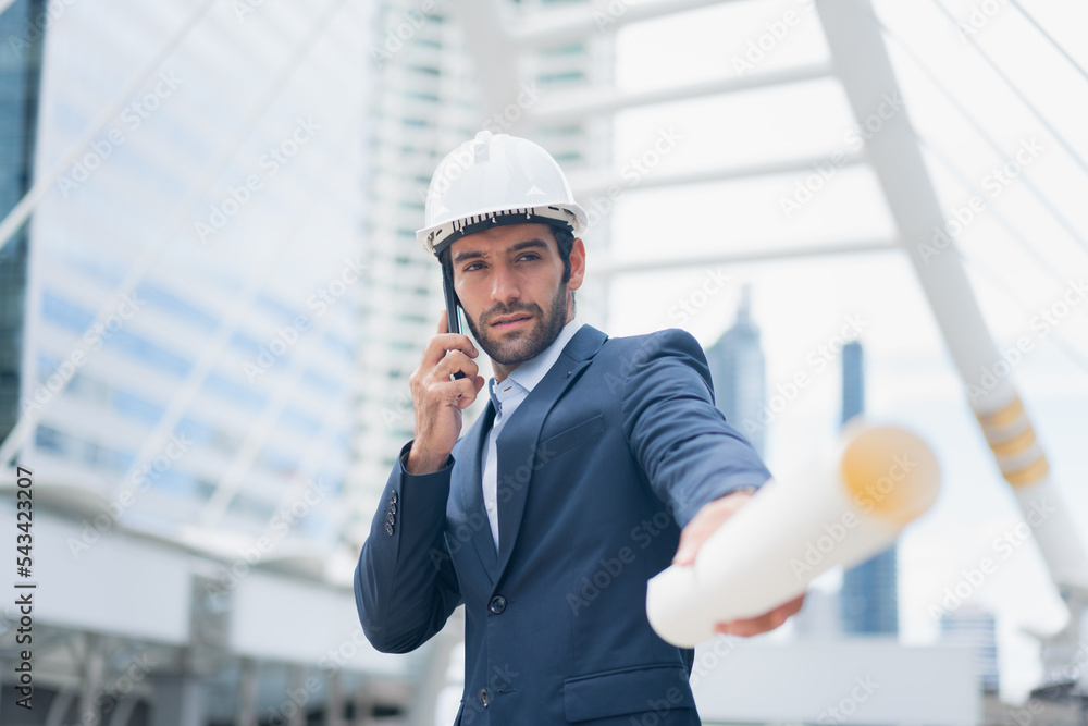 Man engineer standing on construction site. construction manager using walkie talkie. Engineer working on outdoor project and talking on phone