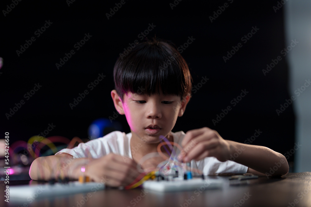 A cute boy constructs metal robot and program it boards microcontrollers on the table STEM education inscription. Programming Mathematics The science Technology DIY workshop at class in the classroom A cute boy constructs metal robot and program it boards microcontrollers on the table STEM education inscription. Programming Mathematics The science Technology DIY workshop at class in the classroom