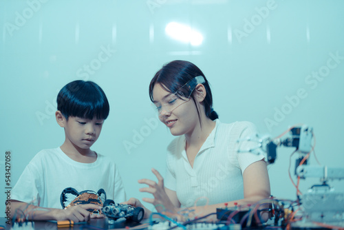 One young boy programming a robot with his science teacher on a primary school female science teacher programming electric toys and robots at robotics classroom   Education Concept