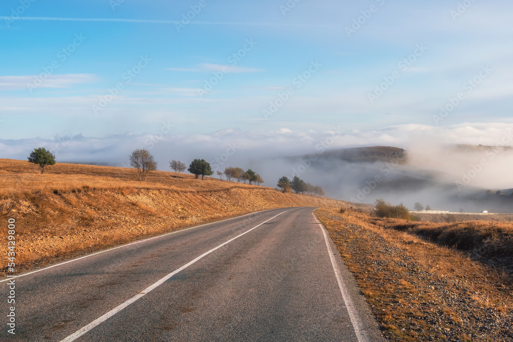 Empty morning highway through the pass in thick fog. Beautiful asphalt freeway, motorway, highway through of caucasian landscape mountains hills at cold weather in mid october.