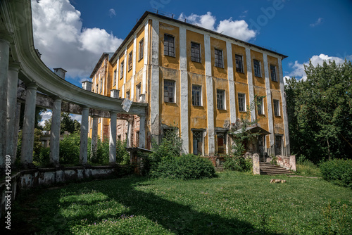 Old abandoned manor in the forest. Shabby walls. Forgotten building. Beautiful trees. Sunny day. Ancient architecture.