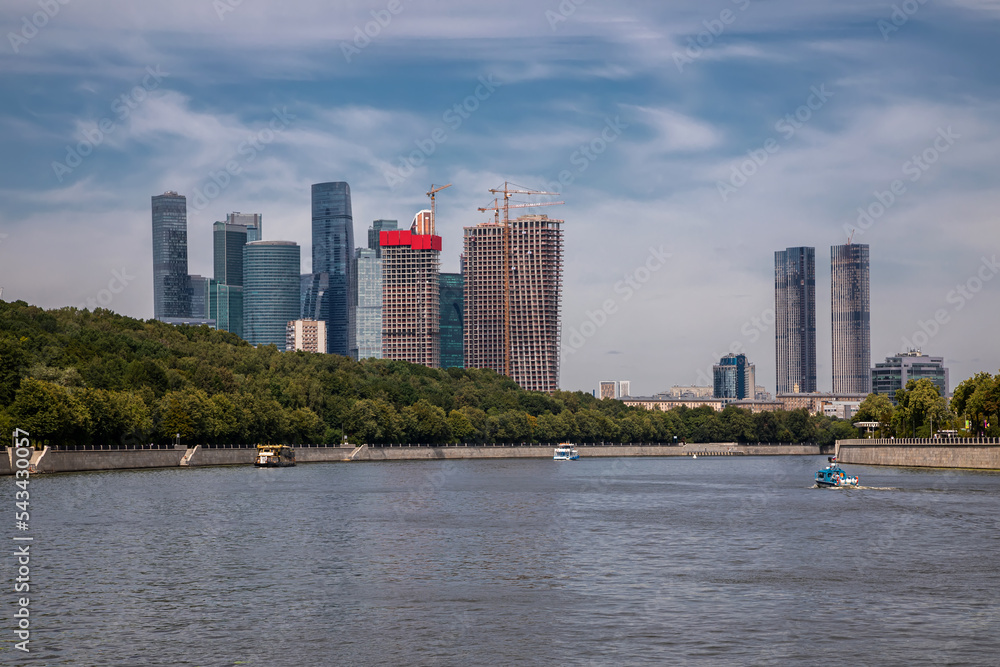 Beautiful tall buildings. Blue sky. Big river. Beautiful green forest. Colorful summer city photo. High skyscrapers.