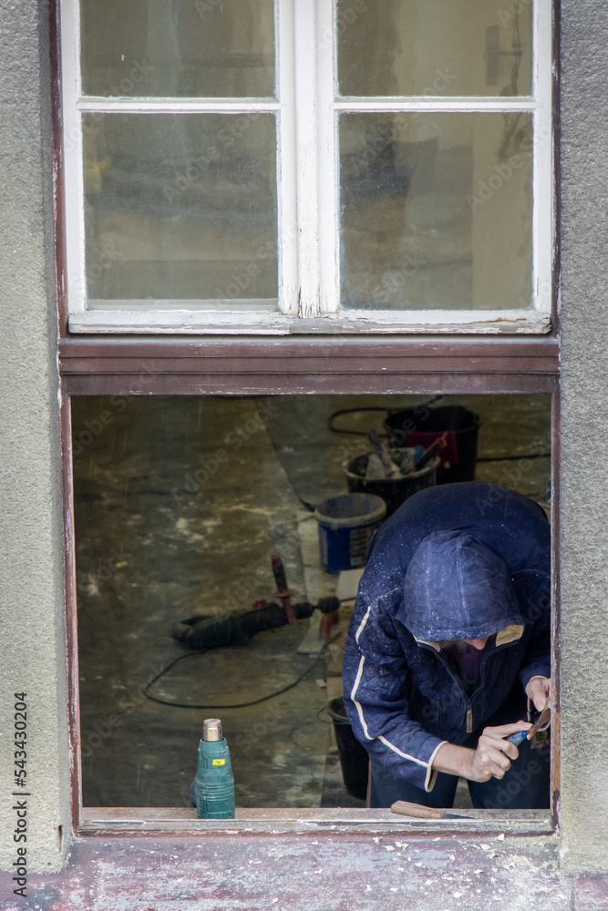 A worker works on the reconstruction of a window in the house A worker works on the reconstruction of a window in the house