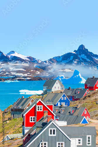 Picturesque village on coast of Greenland a giant iceberg in the background - Colorful houses in Tasiilaq, East Greenland photo
