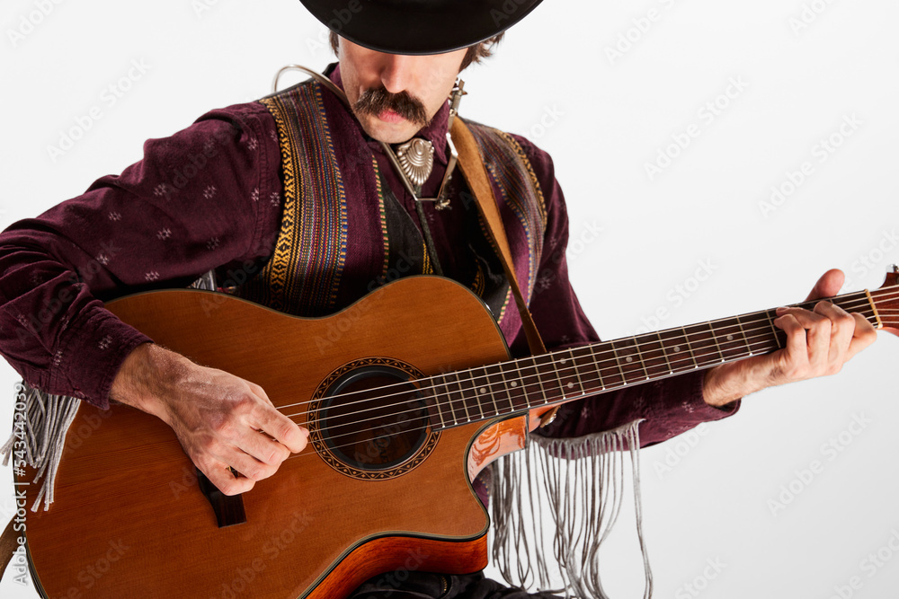 Portrait of man with moustaches in country style clothes playing guitar isolated over white background. Choosing chords Portrait of man with moustaches in country style clothes playing guitar isolated over white background. Choosing chords