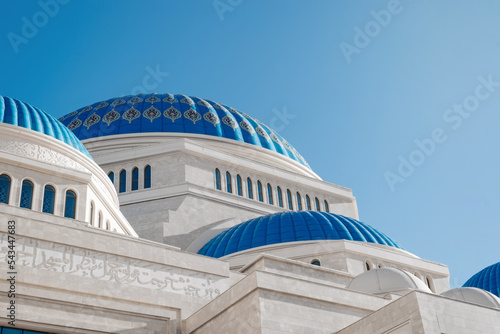 The blue domes of the mosque against the clear sky on a sunny day, outdoors. Close-up of the exterior of religious architecture
