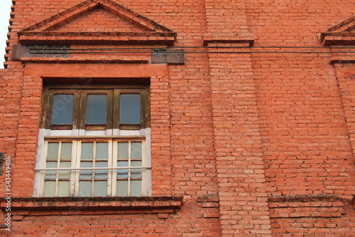 Ventana de la época colonial, antigua y rustica de madera y paredes de ladrillo viejos color rojo